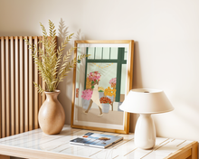 Lade das Bild in den Galerie-Viewer, Dekoration einer Küche im boho-Stil mit Poster mit Motiv einer Frau mit Blumenstrauß vor einem Blumenladen im Sommer