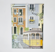 Lade das Bild in den Galerie-Viewer, Der Kalender 2027 für Reiseliebhaber ist hier mit dem Kalenderblatt für den Mai gezeigt. Im Mai präsentiert sich der Kalender mit einer Zeichnung einer urbanen Szene in Lissabon.