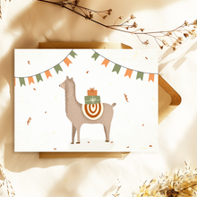 Lade das Bild in den Galerie-Viewer, Eine süße Geburtstagskarte mit einem braunen Lama, das Geschenke trägt und einen bunten Sattel trägt. Das Lama ist von Konfetti und einer Girlande aus orangefarbenen und grünen Flaggen umgeben. Ein passender Briefumschlag aus Kraftpapier ist integriert.