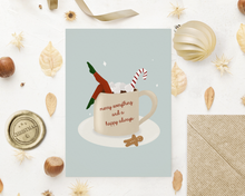 Lade das Bild in den Galerie-Viewer, weihnachtliche Grußkarte mit surrealer Illustration einer Frau, die ein Bad in einer Tasse mit Kakao nimmt und Schriftzug eines englischen Weihnachtsgrußes