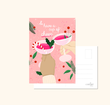 Lade das Bild in den Galerie-Viewer, weihnachtliche Dekoration mit Weihnachtskarte mit Spruch and have a cup of cheer und Bild von zwei mit Sekt anstoßenden Frauenhänden