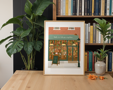 Lade das Bild in den Galerie-Viewer, Bücherregal Dekoration mit Kunstdruck eines gemalten Buchladens in Backsteinhaus
