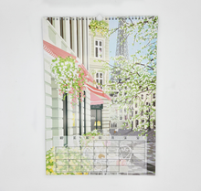 Lade das Bild in den Galerie-Viewer, Kalenderblatt April: Eine Szene im April im Frühling ist illustriert. In der Front ist ein Cafe zu erkennen, im Hintergrund befinden sich Häuser und der Eiffelturm. Florale Details runden das Bild ab.
