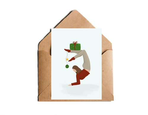 Weihnachtskarte mit Illustration einer Frau in Yogapose, die Weihnachtsgeschenke balanciert