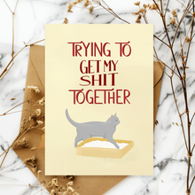 Lade das Bild in den Galerie-Viewer, humorvolle Karte für Katzenfans mit Spruch Trying to get my Shit together und Illustration einer Katze im Katzenklo
